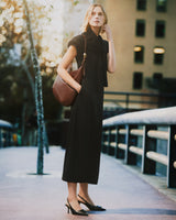 Woman in long dress standing on pathway holding handbag