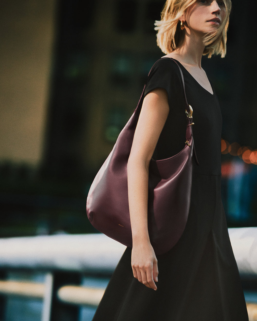 Person walking with a handbag over the shoulder in an urban setting.