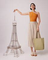 Woman standing next to a wire-frame model of the Eiffel Tower, holding a tote bag.