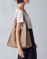 Person wearing a white shirt and black skirt, carrying a large tote bag over the shoulder.