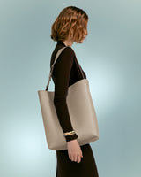 Woman facing to the side carrying a large tote bag