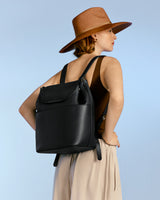 Woman wearing a hat and backpack, looking over her shoulder