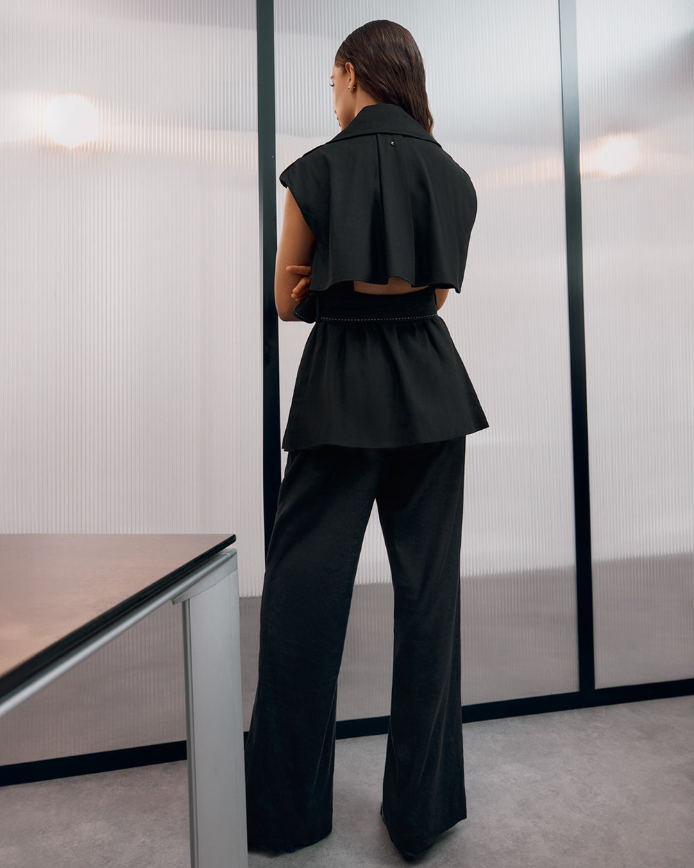 Woman standing with her back to the camera in an indoor setting.