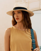 Woman wearing a hat and sleeveless top with a shoulder strap bag.