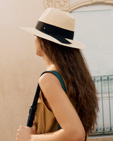 Woman wearing a hat, facing away from the camera, near a door.