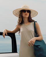 Woman in hat leaning on car door near sea
