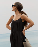 Woman looking over shoulder holding a bag by the sea