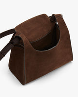 Suede shoulder bag with a structured design and adjustable strap.