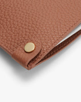 Laptop in a textured sleeve with a metallic snap closure visible.