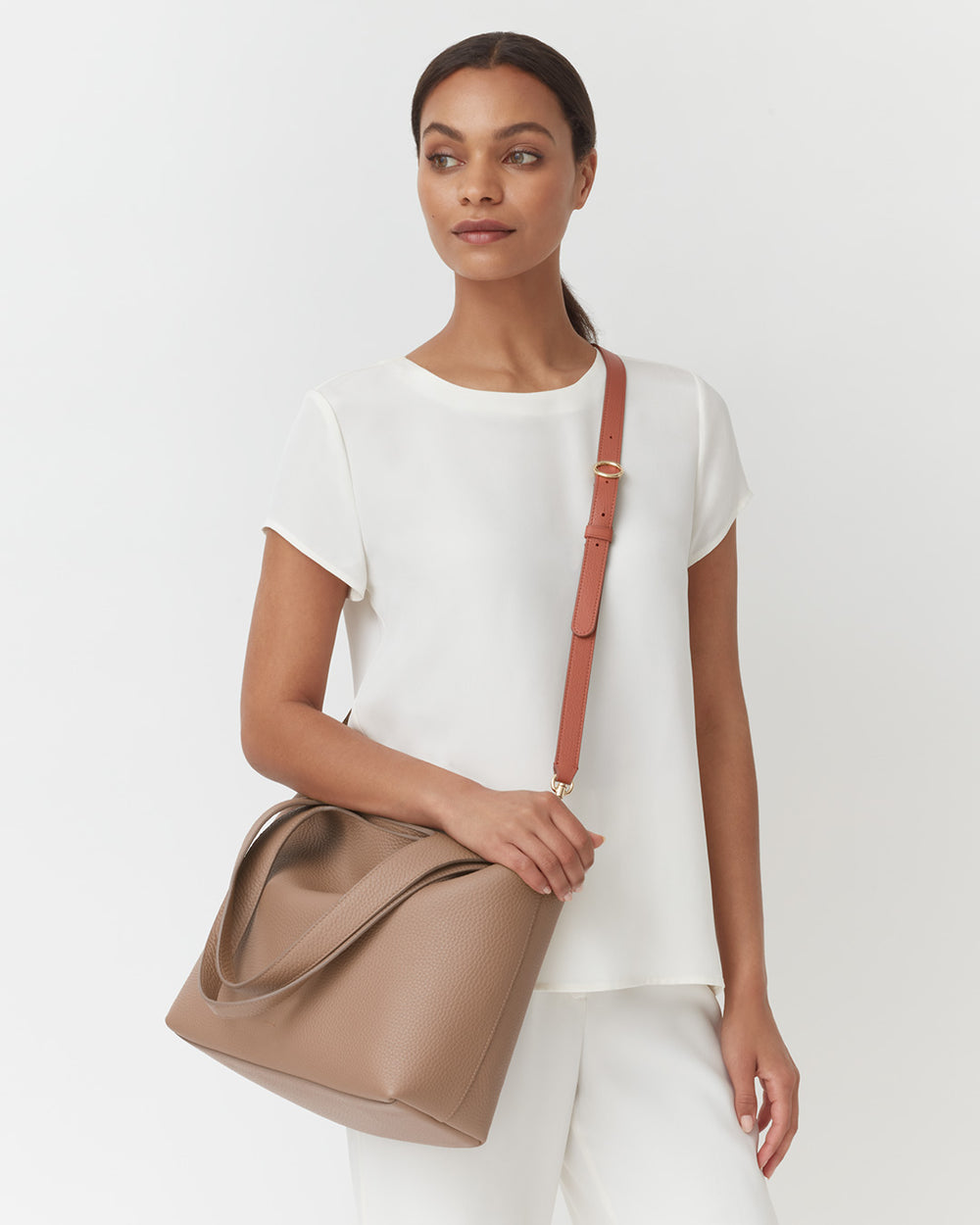 Woman standing with a large handbag over her shoulder.