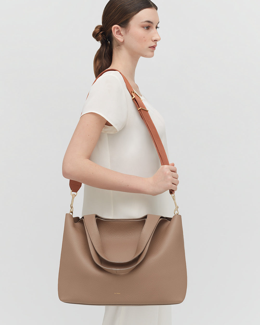 Woman standing sideways carrying a large shoulder bag.