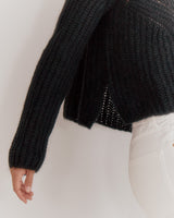 Person in a sweater and pants, partial view focusing on midsection.