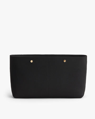 Black handbag with two front pockets and gold-tone rivets.