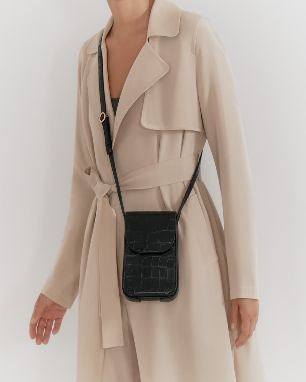 Person wearing a trench coat with a crossbody bag.