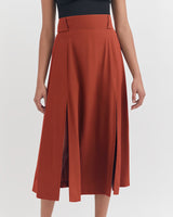 Person wearing a skirt with a wide waistband and mid-length pleats.