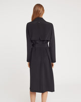 Woman in a belted coat seen from the back.