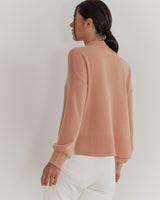 Woman in a sweater viewed from the back, standing.