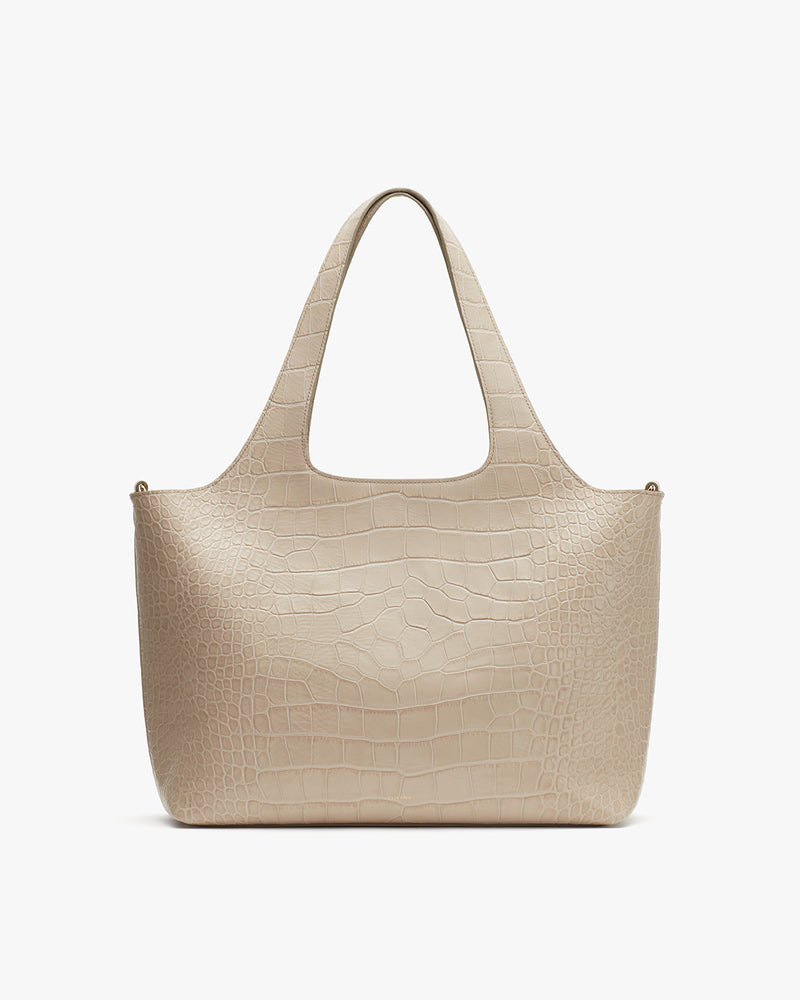 Handbag with two handles and textured surface.
