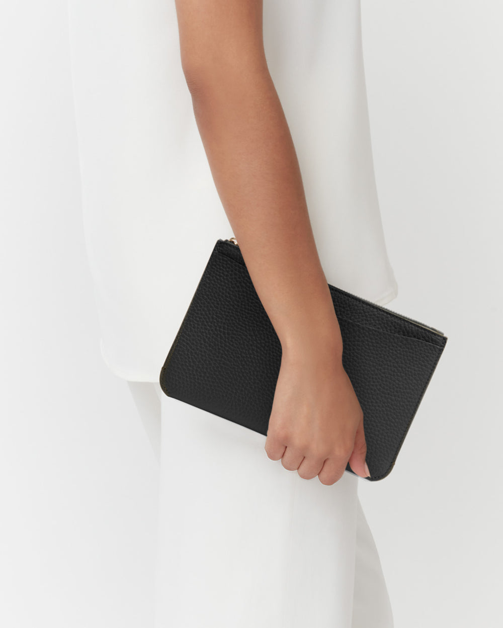 Person holding a clutch bag by their side.