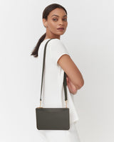 A woman wearing a top with a shoulder strap bag looking over her shoulder.