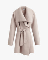 Wool coat with large lapels and a belt hanging on a white background.