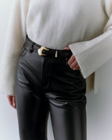 Person wearing a long-sleeve top, black pants, and a belt with a gold buckle