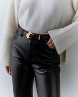 Person wearing a sweater with bell sleeves, a belt, and leather pants