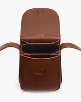 Open leather bag with flap and handles, showing interior compartments