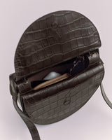 Open croc-embossed leather bag with visible zipper pouch and sunglass.