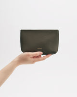 Hand holding a small leather pouch against a plain background