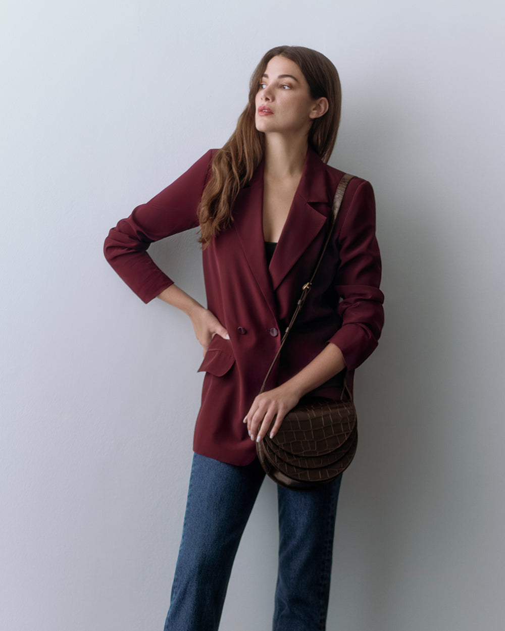 Woman wearing a blazer and jeans, holding a croc-embossed leather bag