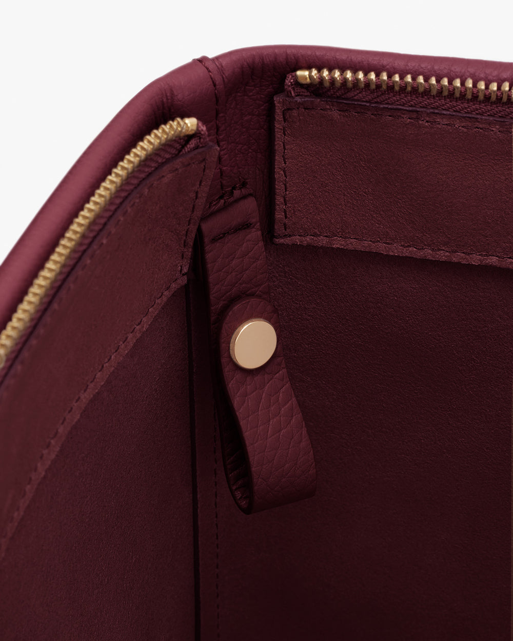 Close-up of a travel bag's interior showing a zipper and a strap with a button.