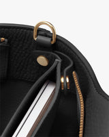 Bag interior with a pocket and metal hardware, showing an item partially inside the pocket.