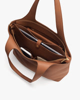 Open handbag with compartments holding a laptop, phone, and some accessories