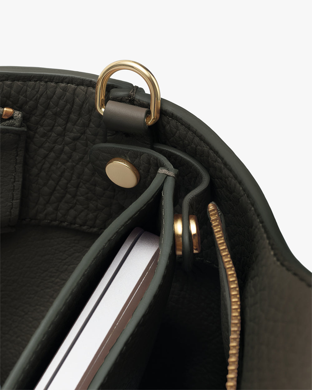 Close-up of a bag's interior with a notebook and metallic accessory rings.