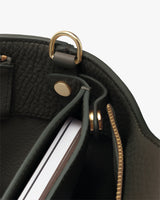 Interior of a bag with a clasp and a zippered pocket containing a notebook.