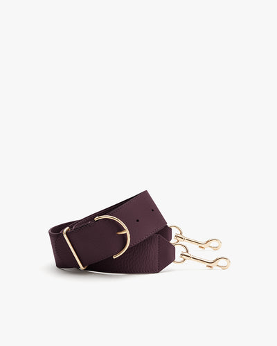 A folded strap with gold clips and a gold D-ring.