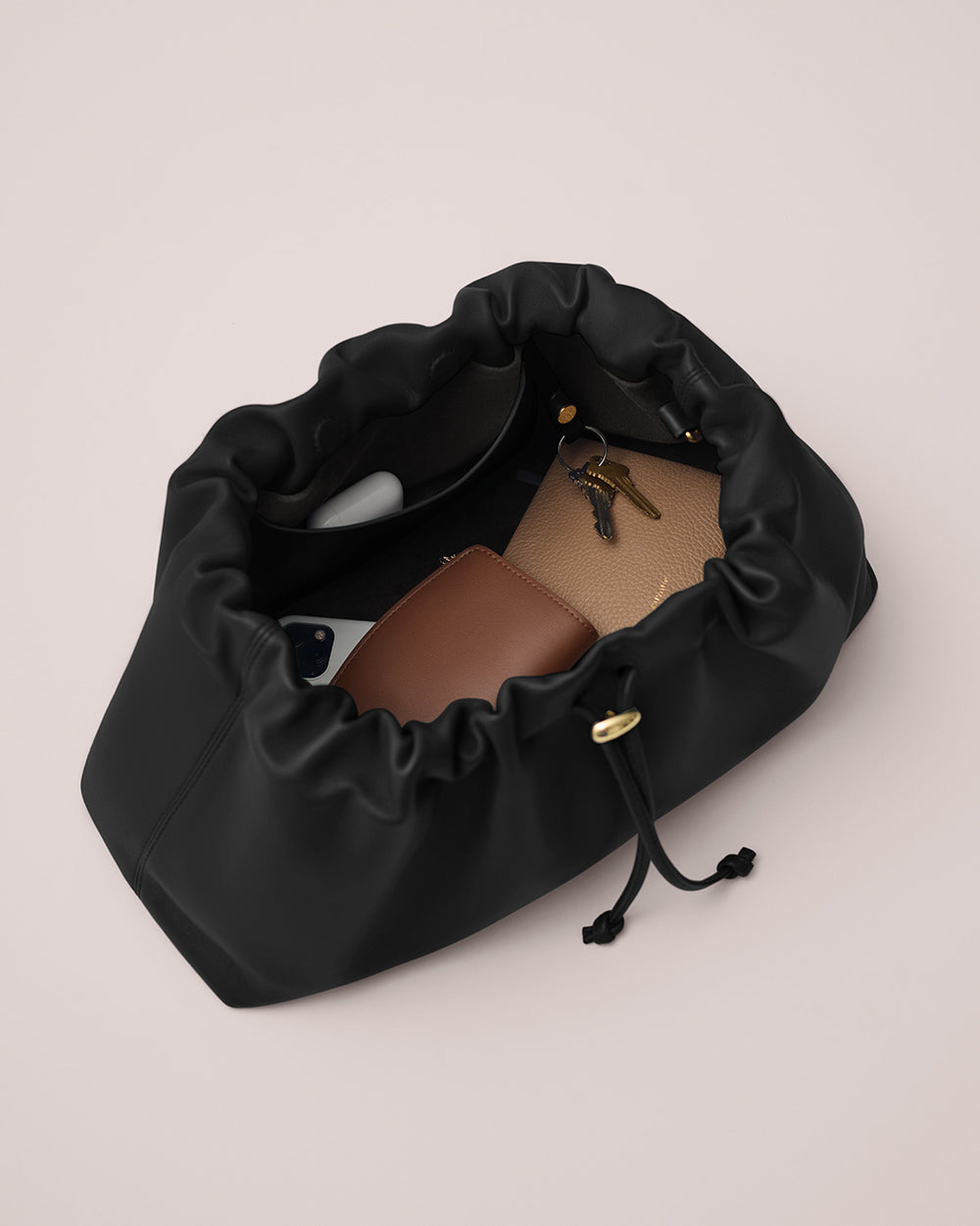 Open drawstring bag with sunglasses, wallet, and keys inside.