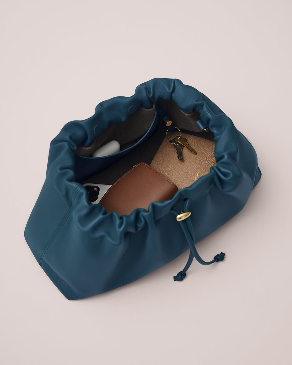 Drawstring bag open, revealing keys, wallets, and an earbud inside.