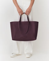 Person holding large tote bag, wearing long pants and shoes.