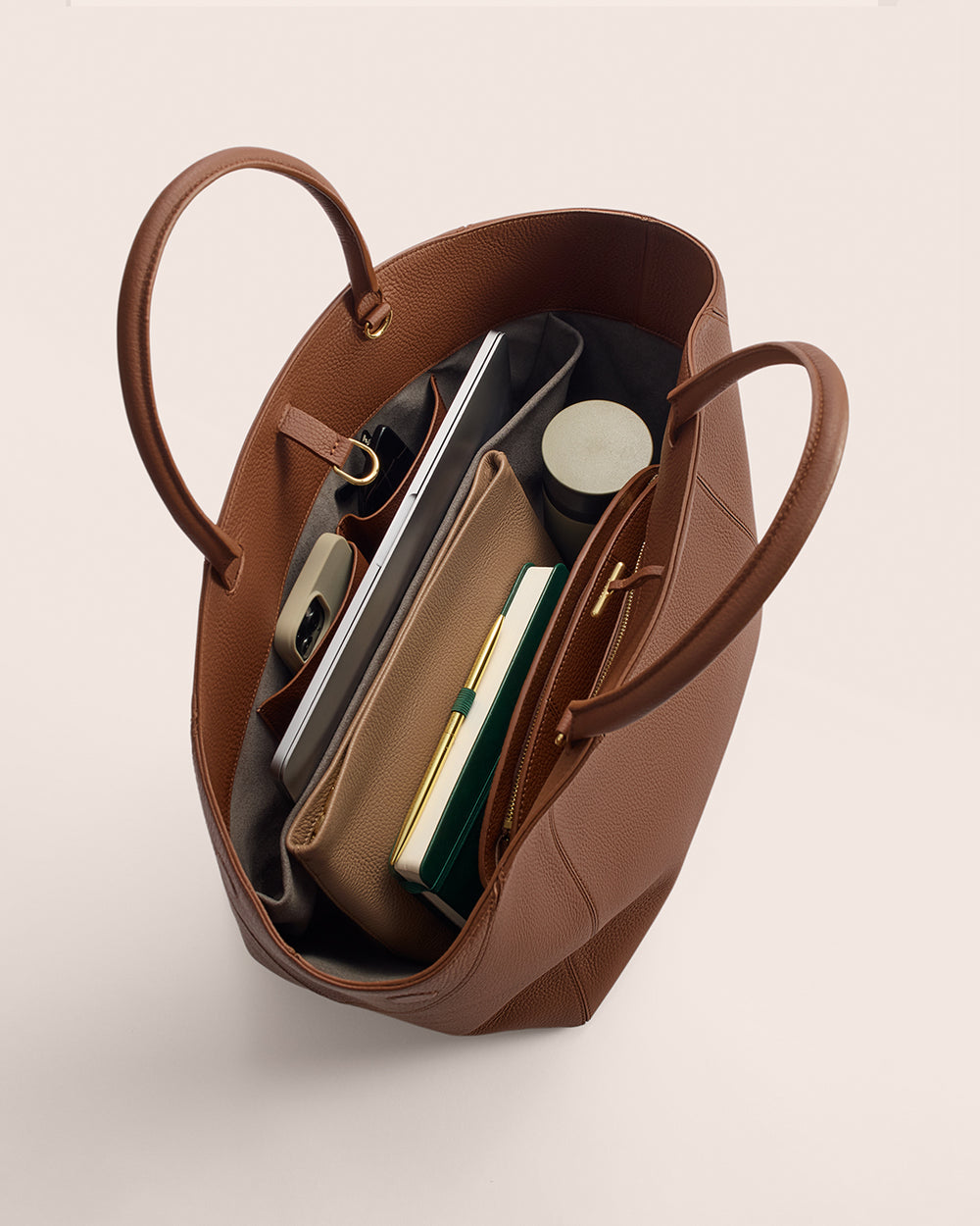 Open tote bag filled with items like books, a pouch, and a bottled container.