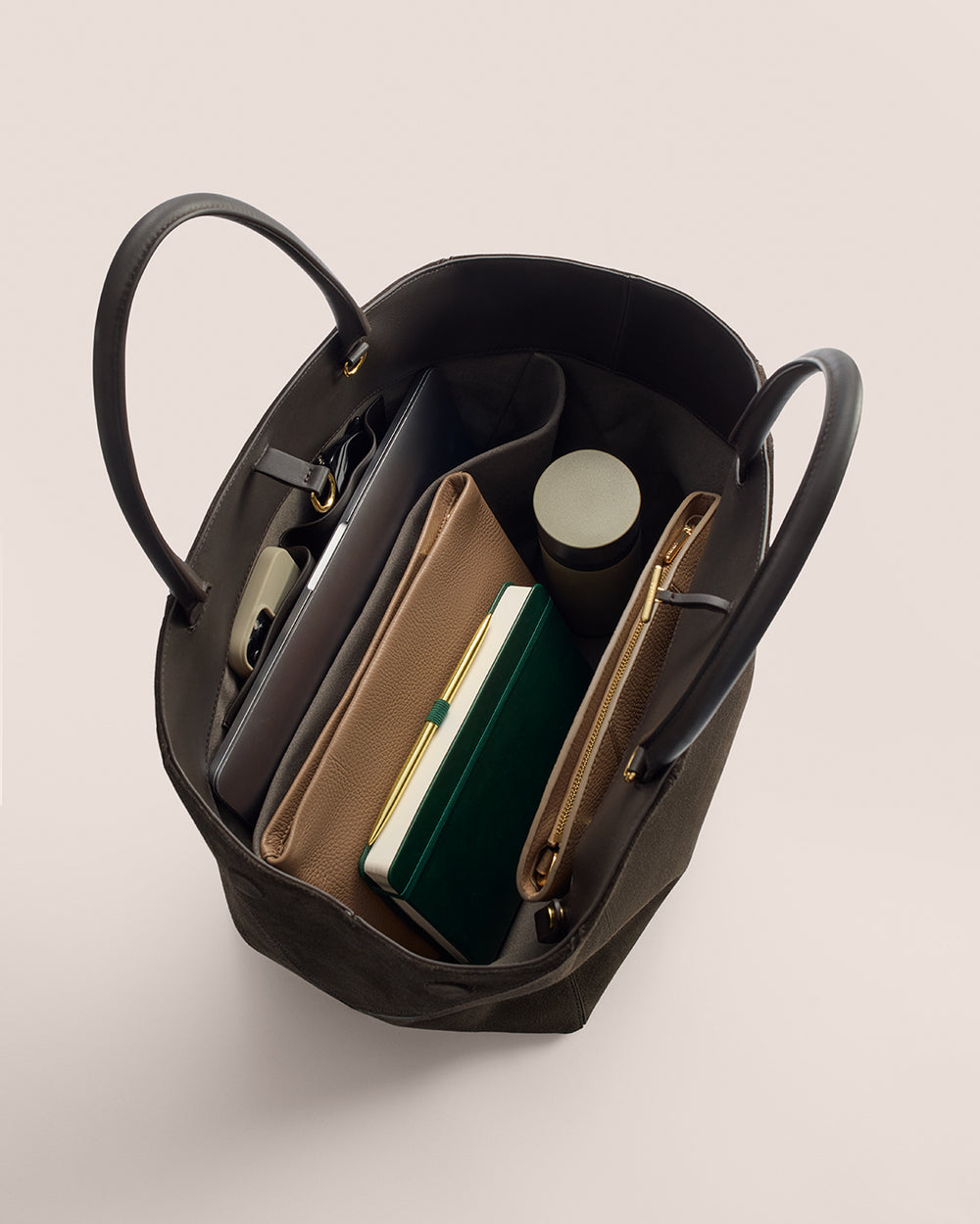Open tote bag with books, a wallet, and a cylindrical container inside.