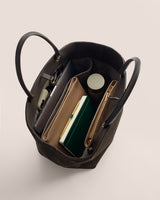 Open tote bag with books, a wallet, and a cylindrical container inside.