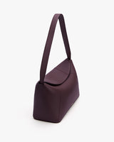 Shoulder bag with long strap and flap closure on white background.