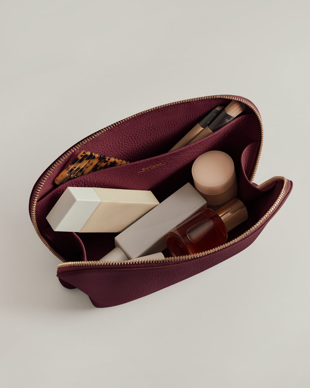 Open makeup bag with various cosmetics and a brush inside.