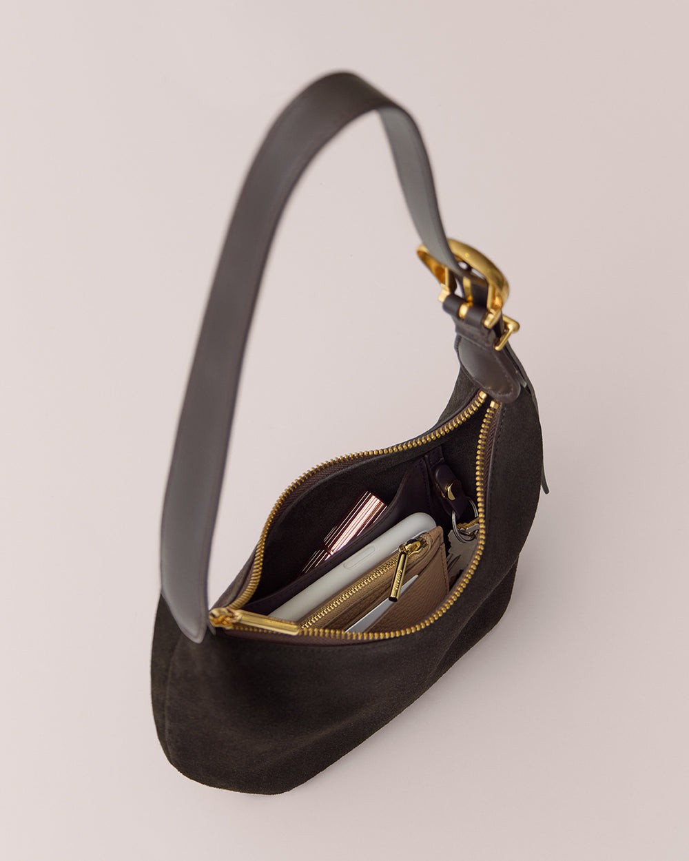 Handbag with an open zipper showing a book, wallet, and phone inside.