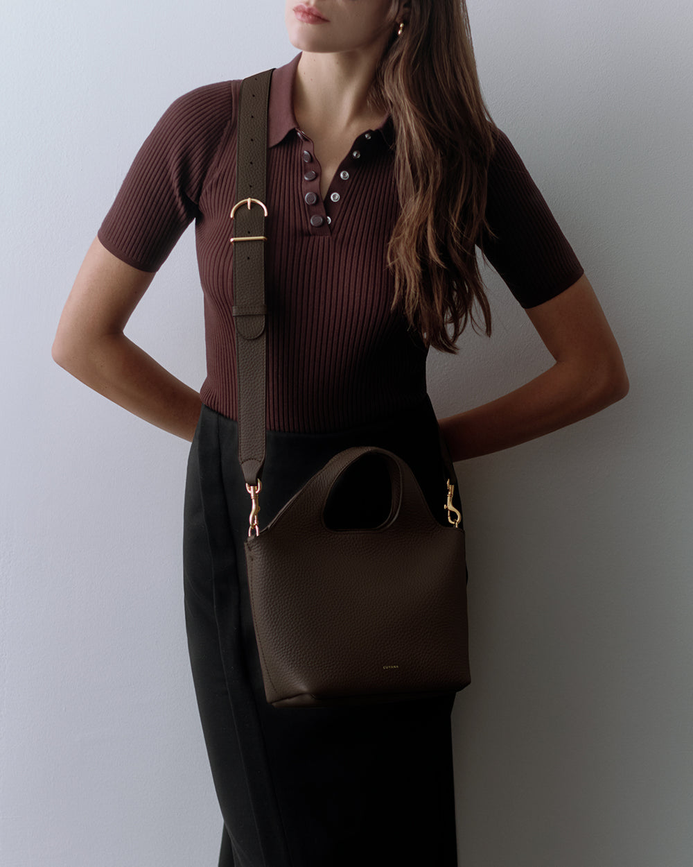 Person with a shoulder bag, arms on hips.