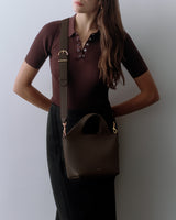 Person with a shoulder bag, arms on hips.