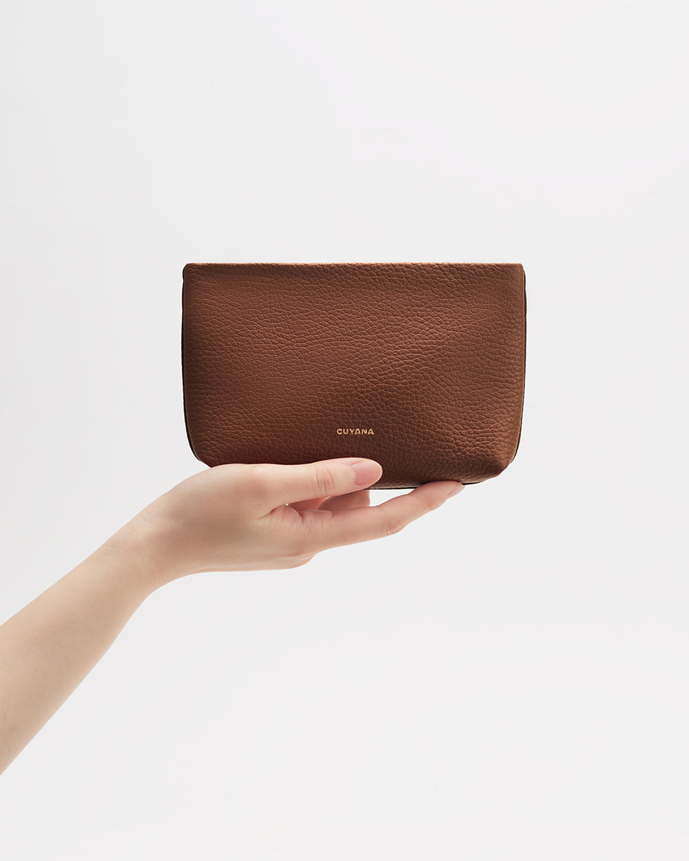 Hand holding a small pouch against a plain background.