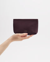 Hand holding a small pouch against plain background.